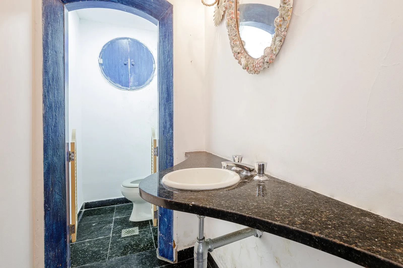 A bathroom with a round window and a marble vanity