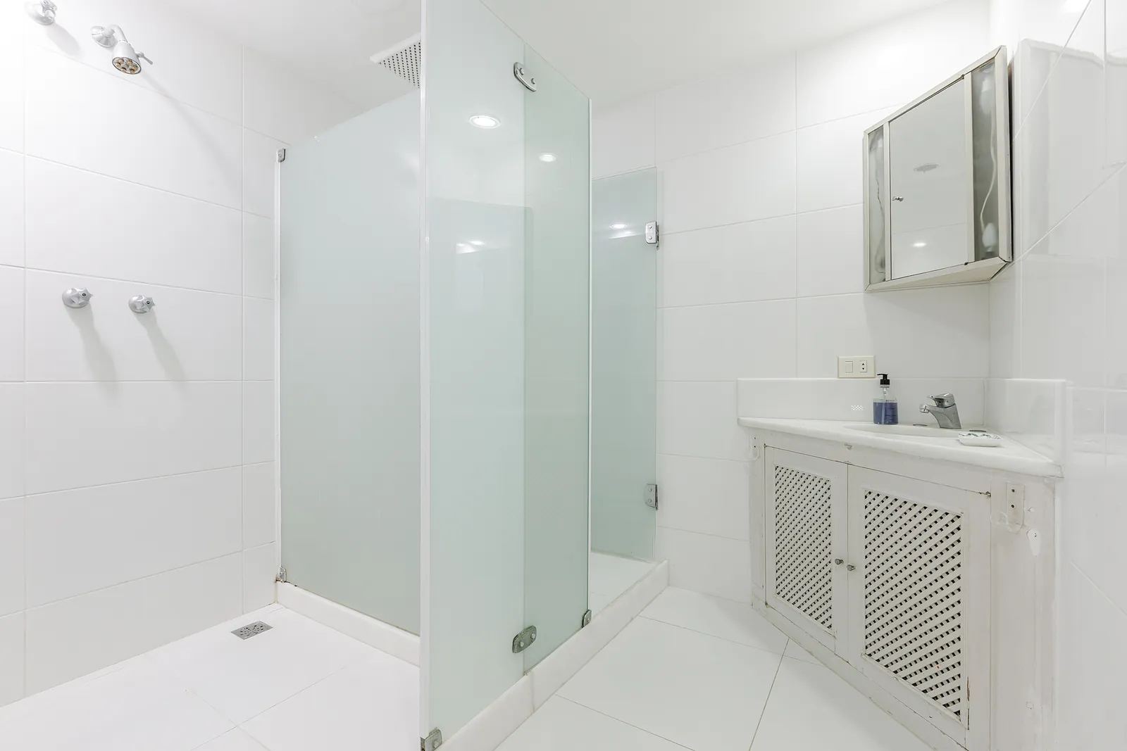 A bathroom with a glass shower and a vanity