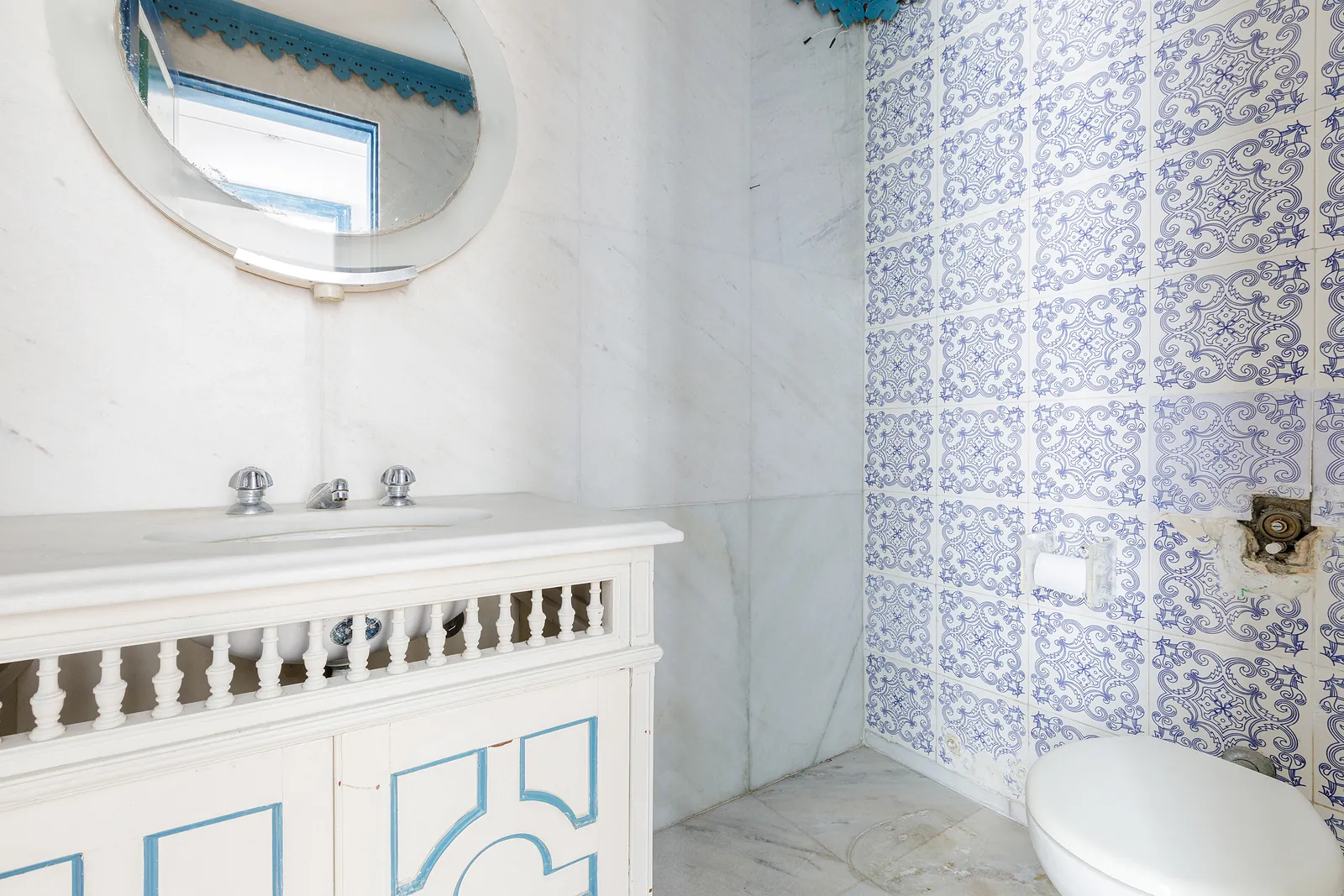 A bathroom in blue tile with a round mirror