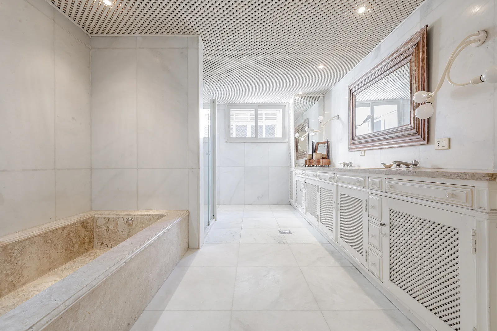 A marble bathroom with a bathtub and a walk-through