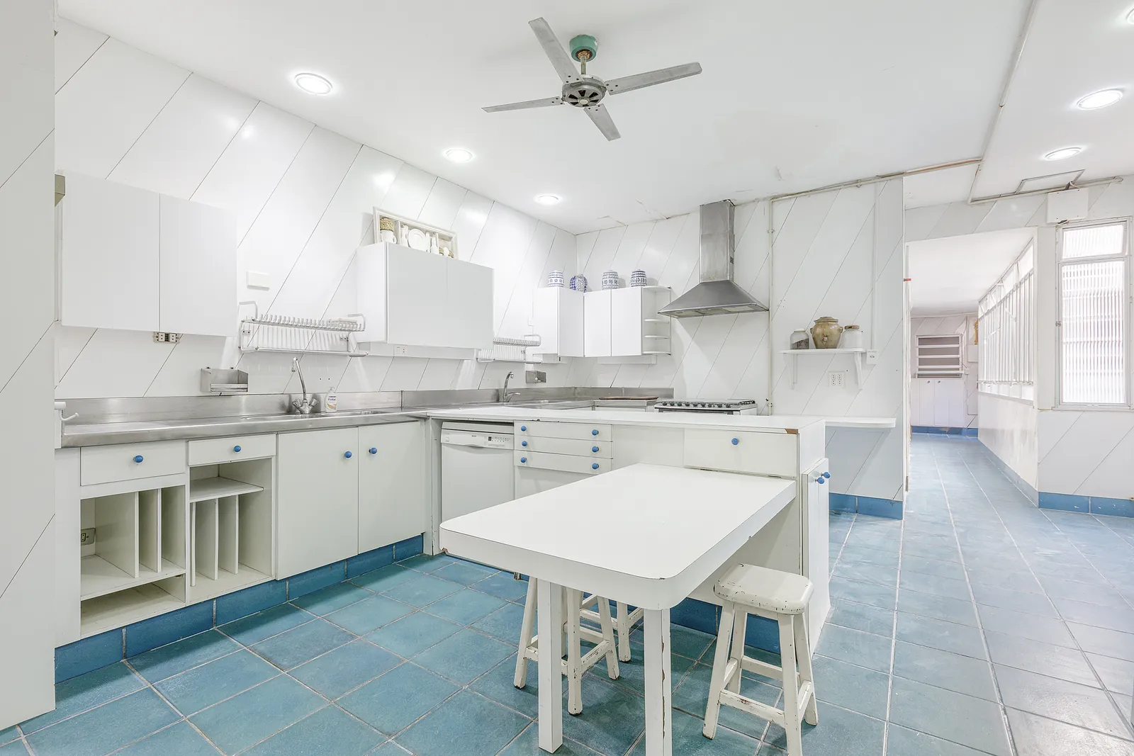 A kitchen in steel and white with an island, blue floor