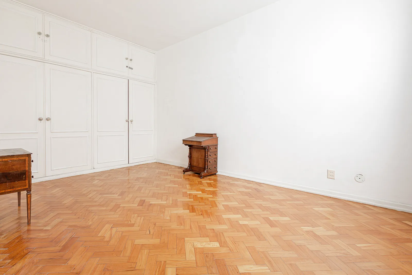 A bedroom with a fitted wardrobe and parquet floor