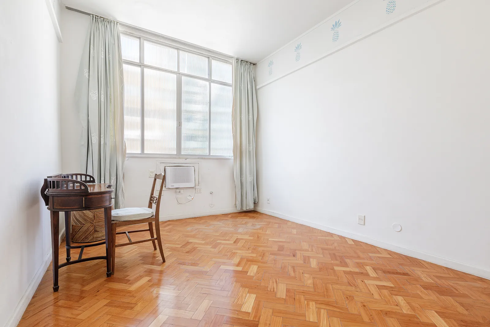 A bedroom with a window and a parquet floor