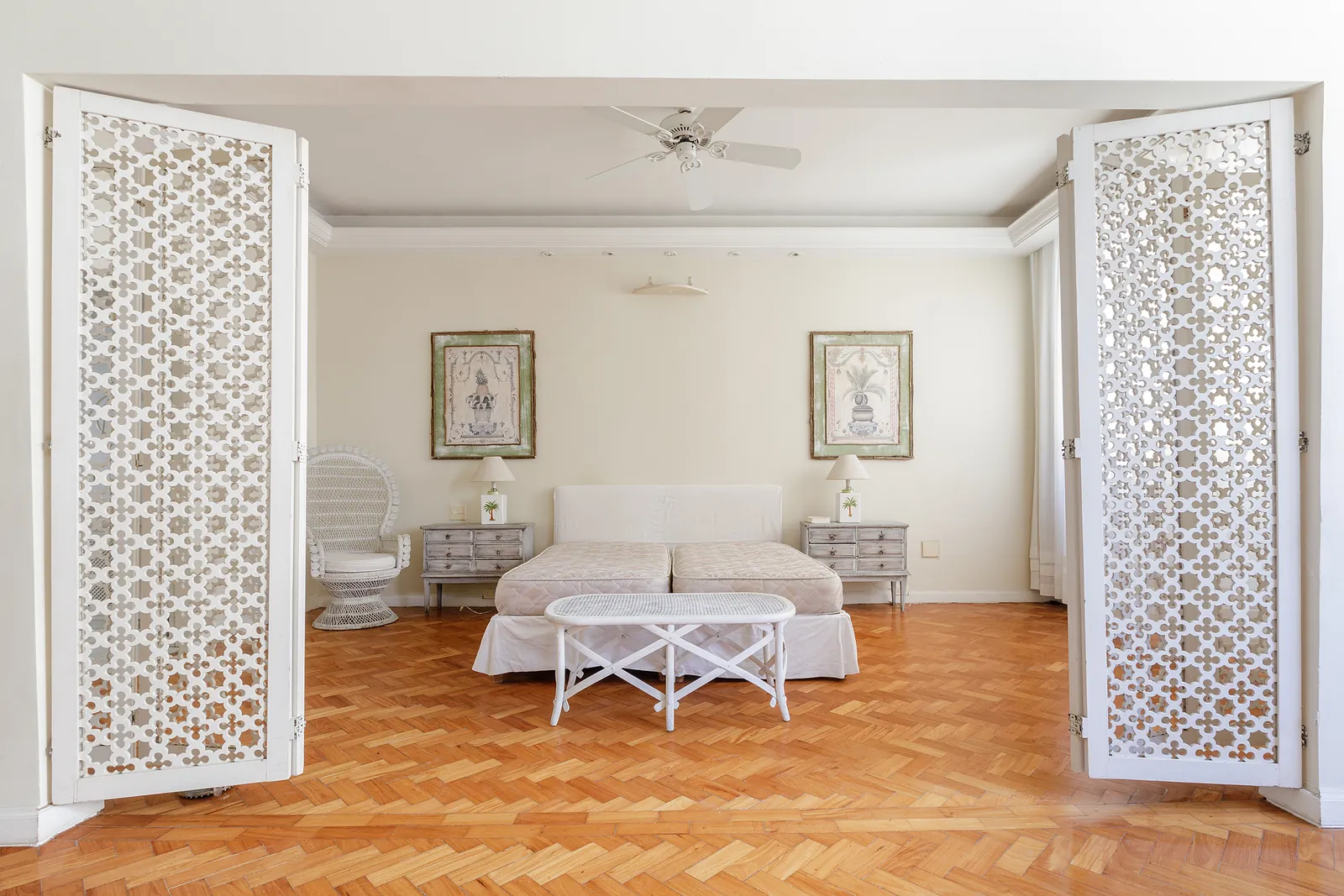 A bedroom divided by a screen, a ceiling fan above