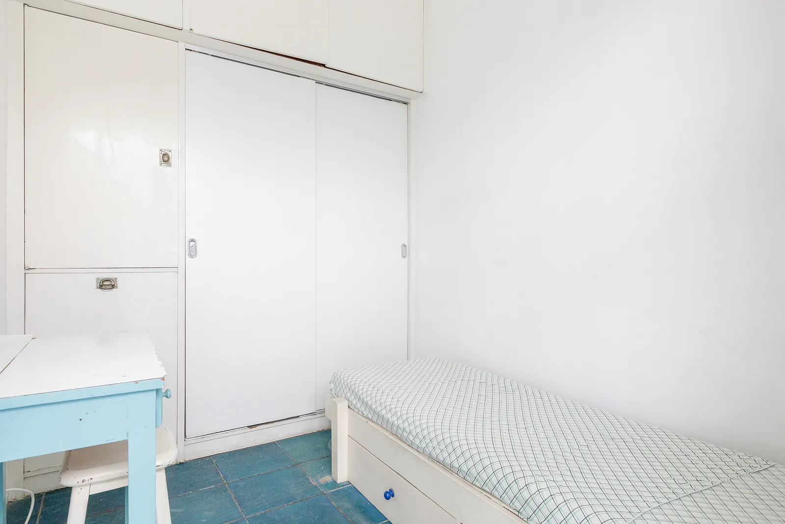 A simple bedroom with a bench and a blue floor