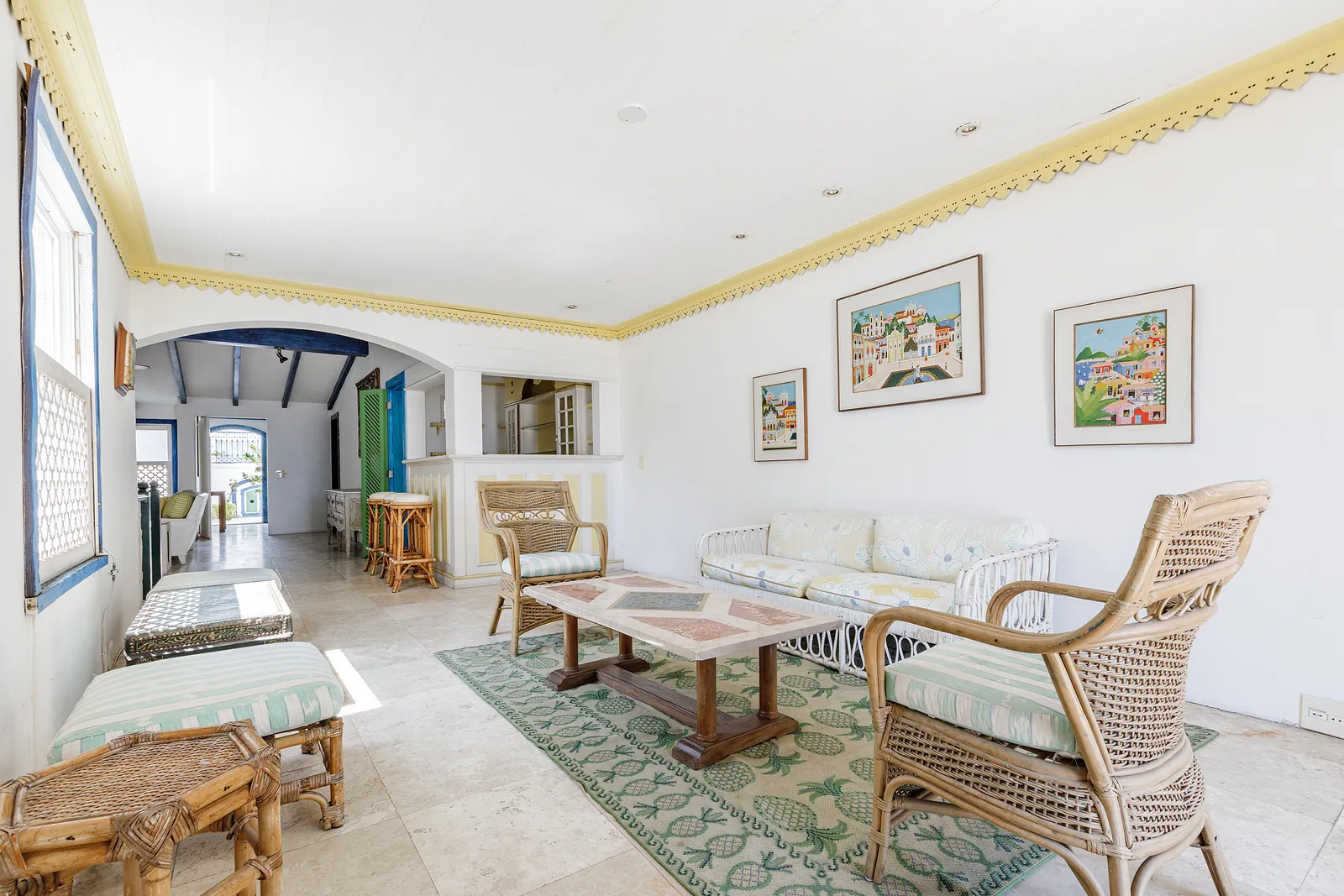 A reception room under a beamed ceiling, rattan seating and artwork