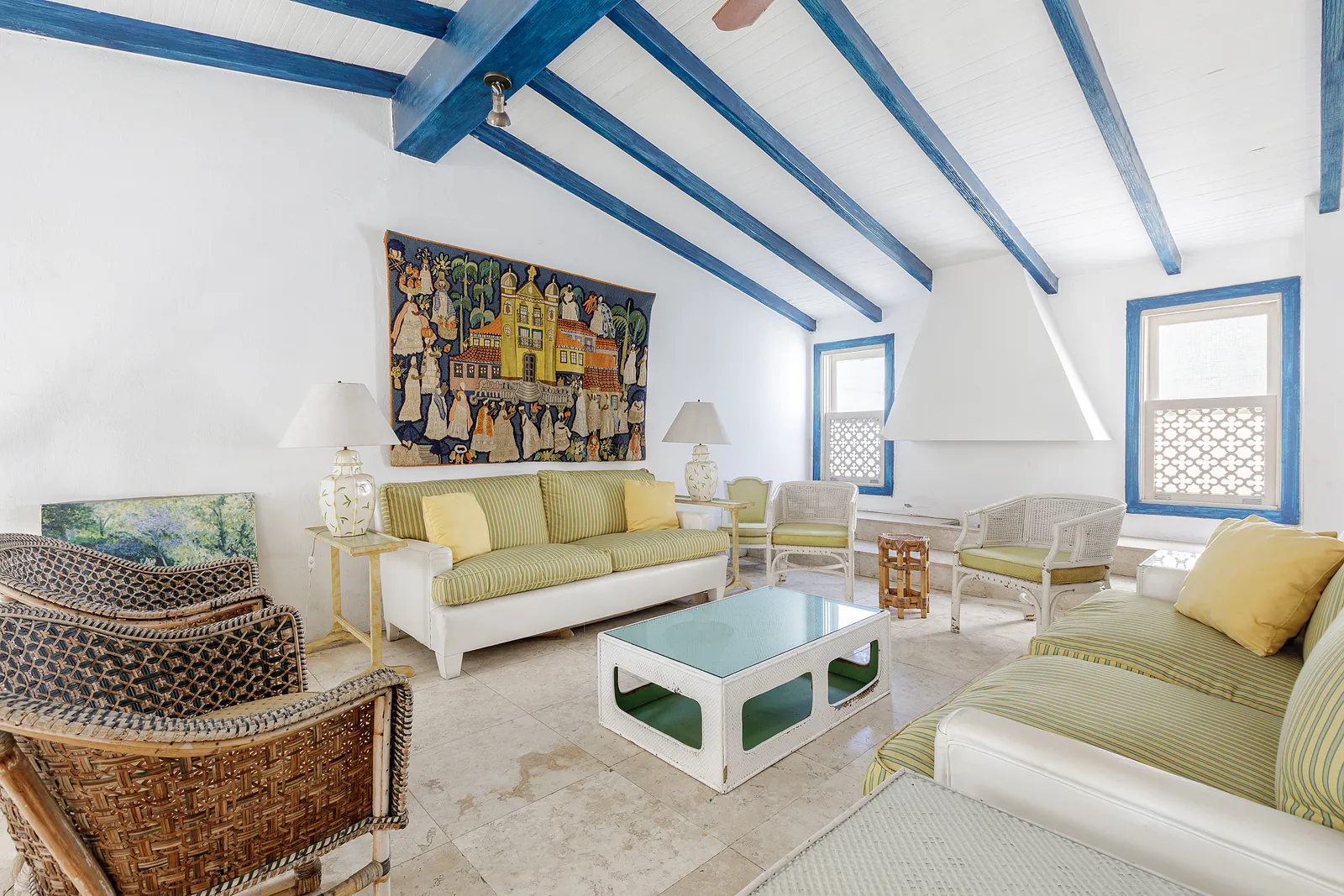 A reception room under beams, pale sofas and framed art