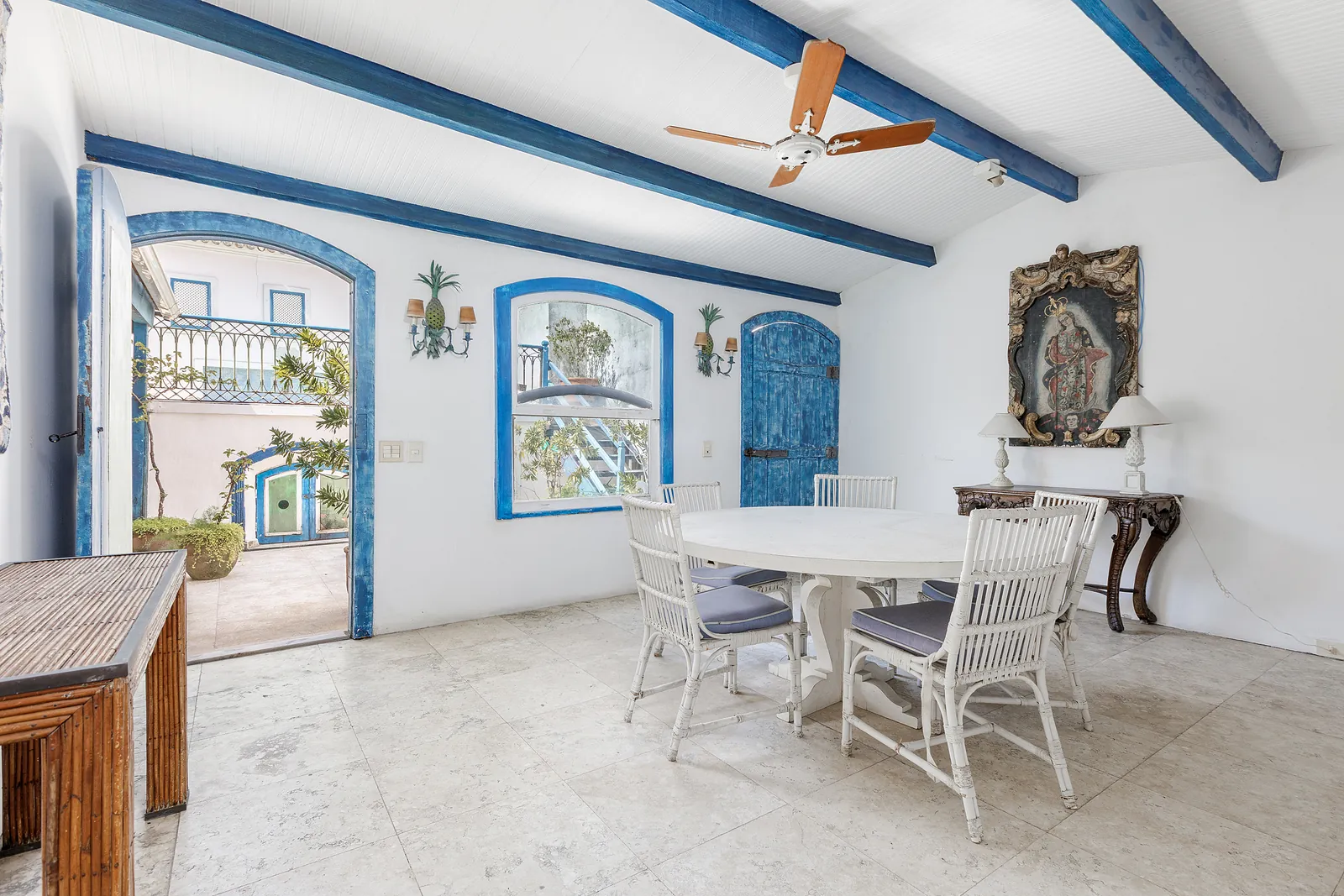 A dining area under a ceiling fan, tiled arches alongside