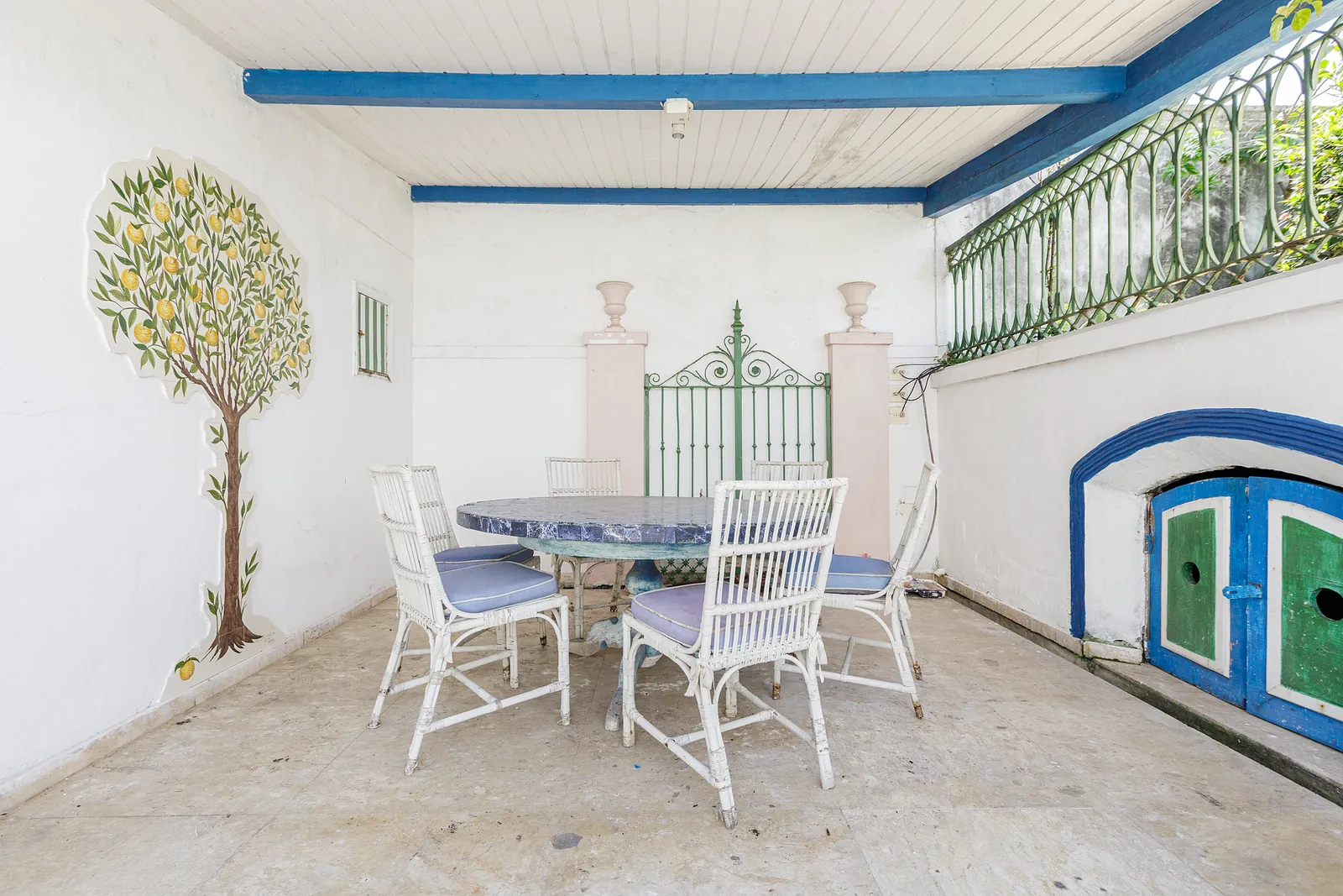A covered terrace set for dining, topiary and white chairs