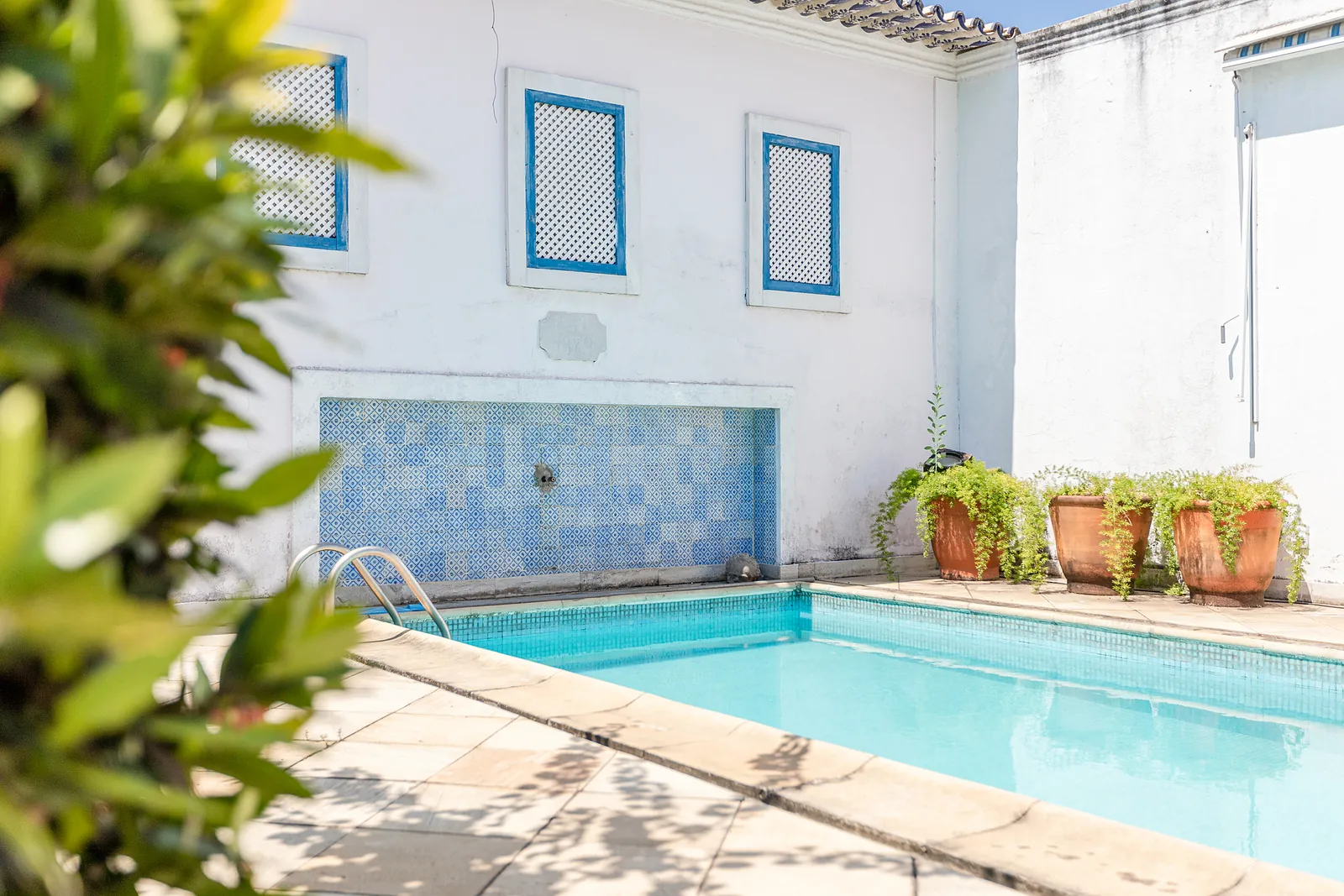 A corner of the pool beside a blue-tiled fountain wall