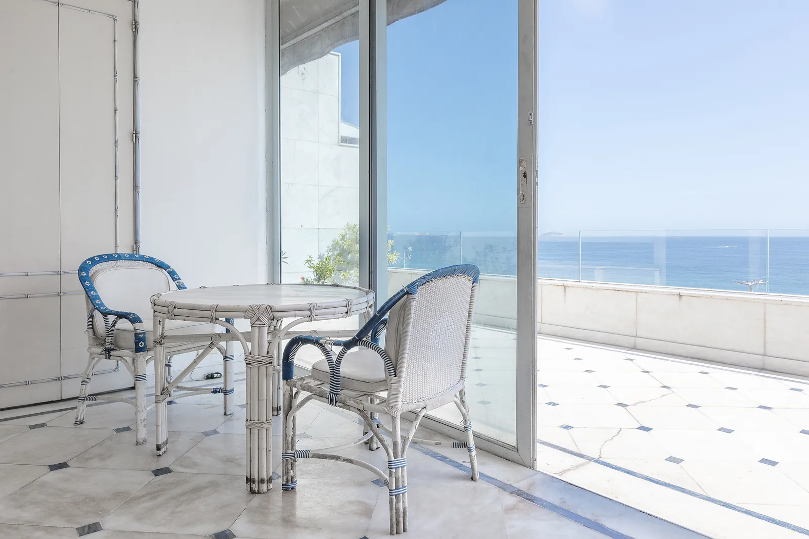A terrace corner with a table, the sea through the glass
